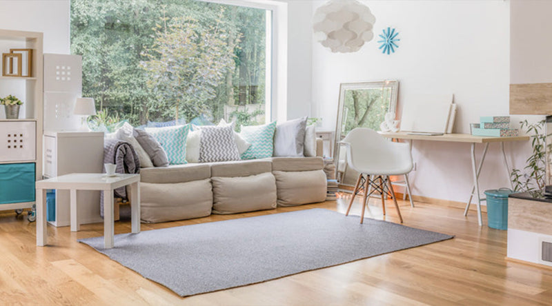 "Lichte woonkamer met lichte tinten en een lichte houtlook vloer"