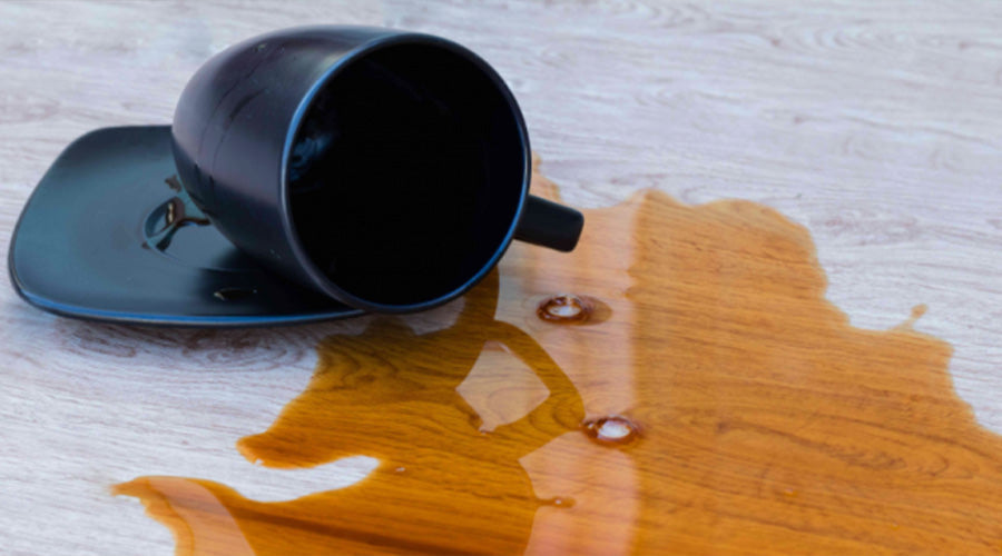 Gemorste drank op een houten vloer, toont het belang van een sterke en onderhoudsvriendelijke vloerafwerking.