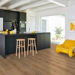 lichte beige eiken vloer met brede planken in houten patroon in moderne keuken met zwarte kasten en gele accenten