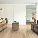 lichte beige eiken vloer met brede planken en een subtiele houtstructuur in een modern lichte woonkamer met bruine stoffen banken en een beige poef als salontafel