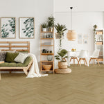 lichte beige vloer met visgraat patroon en brede planken, gecombineerd met een lichte houten bank met groene en witte kussens en natuurlijke decoratie in een lichte, open woonkamer en eetgedeelte