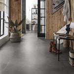 donkergrijze vloertegels met fijne, subtiele structuur in een ruime hal met houten wandbekleding en zwarte metalen accenten