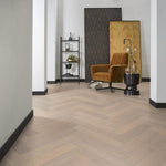 lichte visgraatvloer met brede planken in licht wit es eiken met matte structuur in moderne woonkamer met bruin okergele fauteuil en zwarte accenten