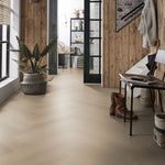 lichte vloer in visgraatpatroon met brede planken in zacht beige eiken, gecombineerd met houten wandpanelen in warme bruine tinten en een industriële zwarte stalen deur met glas.