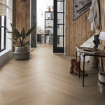 lichte beige eiken visgraatvloer met brede planken in een entree met houten wandbekleding en zwart metalen deurkozijnen