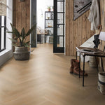 lichte vloer in visgraatpatroon met brede planken in licht beige eiken kleur, gecombineerd met houten wandbekleding en natuurlijke accessoires in halruimte met veel daglicht
