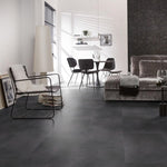 donkergrijze tegelvloer met grote matte tegels zonder patroon in moderne woonkamer met minimalistisch zwart metalen stoelen en lichtgrijze zachte bank