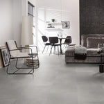 lichte grijs tegelvloer met grote matte tegels en subtiel golvend streeppatroon in moderne woonkamer met minimalistisch zwart metalen stoel en grijze velvet bank