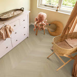 licht beige eiken vloer in visgraatpatroon met fijne houtstructuur in een lichte babykamer met rotan wieg en pluchen octopusknuffel