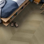 licht beige eiken visgraatvloer met matte structuur in slaapkamer naast laag houten bed met open opbergruimte en beige pantoffels op de vloer