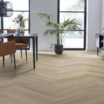 lichte vloer in visgraatpatroon met brede planken en subtiele nerven in licht eiken kleur in lichte moderne eetkamer met bruine stoelen en veel daglicht