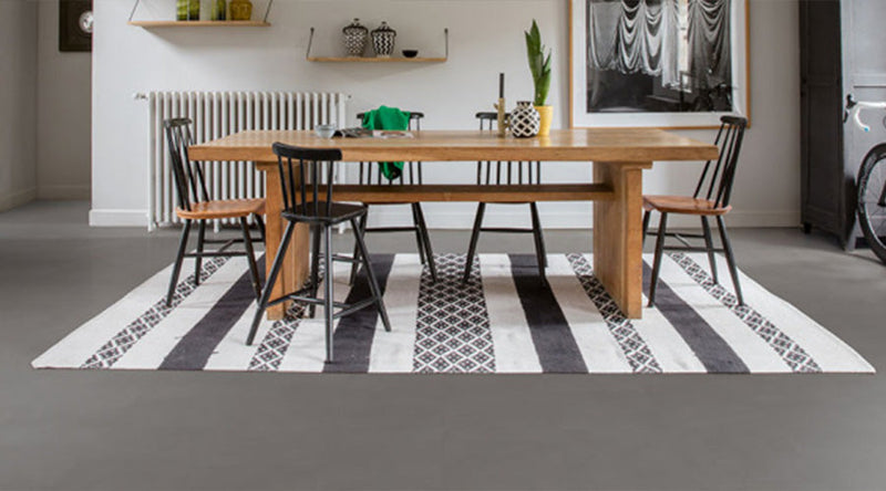"Houten eettafel met een kleed op een betonlook vloer"