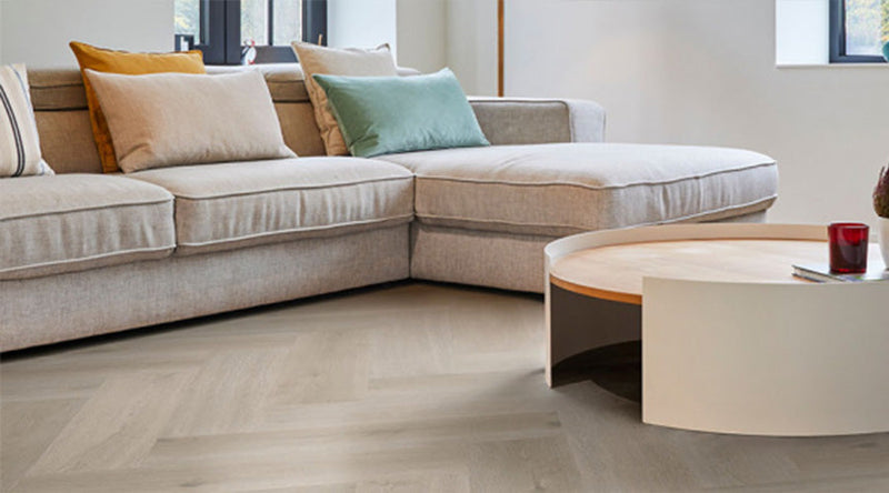 Moderne woonkamer met lichte visgraat vloer, zachte kleuren en een rustige, elegante interieuruitstraling.