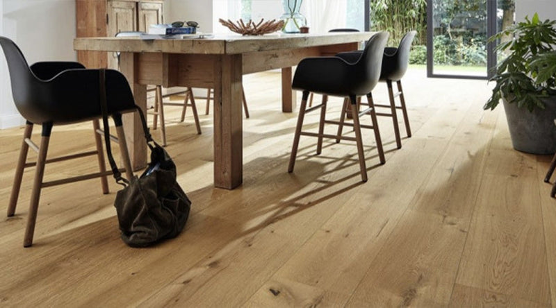 "Houten eettafel met donkere stoelen een een geschuurde houten vloer"