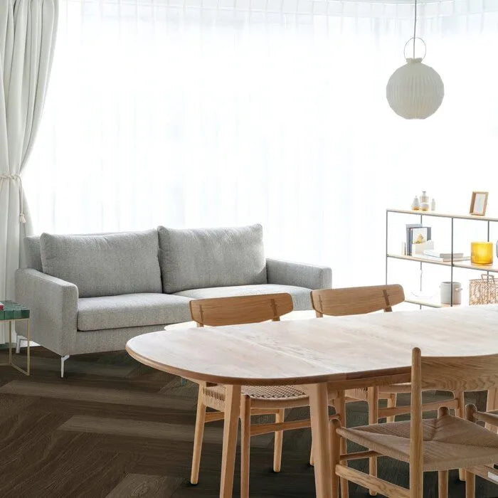 donkerbruin eiken visgraatvloer met matte structuur in lichte woonkamer met grijs stoffen bank en licht houten eetkamertafel met bijpassende stoelen