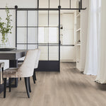licht eiken vloer met brede planken en een subtiele houtstructuur in een lichte, natuurlijke tint onder een moderne eethoek met velvet beige stoelen en een industriële zwarte schuifdeur van glas en staal