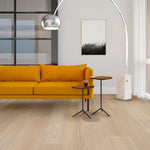 lichte vloer in beige eiken met brede planken en subtiele houtnerfstructuur, geplaatst in moderne woonkamer met mosterdgele bank en metalen bijzettafels met houten blad