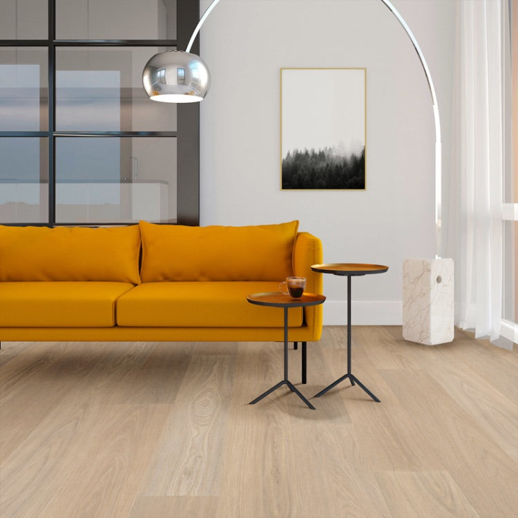 lichte vloer in beige eiken met brede planken en subtiele houtnerfstructuur, geplaatst in moderne woonkamer met mosterdgele bank en metalen bijzettafels met houten blad