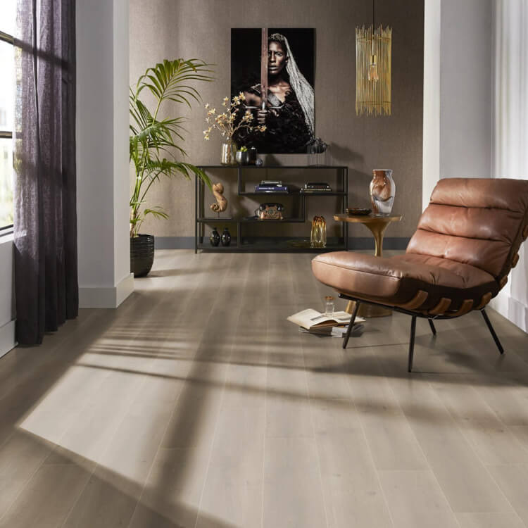 lichte vloer in brede planken met een zachte natuurkleur en een matte uitstraling, gecombineerd met een leren fauteuil en een minimalistisch interieur met planten en kunst aan de wand