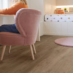 licht eiken vloer met brede planken en zichtbare houtnerfstructuur in slaapkamer met roze fluwelen fauteuil en ronde roze vloerkleed
