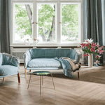 lichte vloer in visgraatpatroon van breed hout met zachte beige eiken kleur, moderne woonkamer met lichtblauwe bank en grote ramen