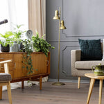lichte grijsbruine vloer met brede planken in houtstructuur in woonkamer met retro houten dressoir, groene planten en een beige bank met donkergroen kussen