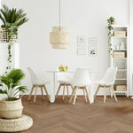 Lichte vloer met brede planken in een visgraatpatroon, licht warm bruin eiken kleur, gecombineerd met wit Scandinavisch design eetkamermeubilair en natuurlijke rotan accessoires.