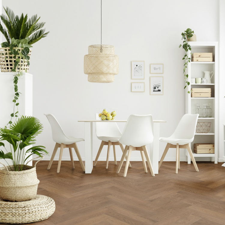 Lichte vloer met brede planken in een visgraatpatroon, licht warm bruin eiken kleur, gecombineerd met wit Scandinavisch design eetkamermeubilair en natuurlijke rotan accessoires.