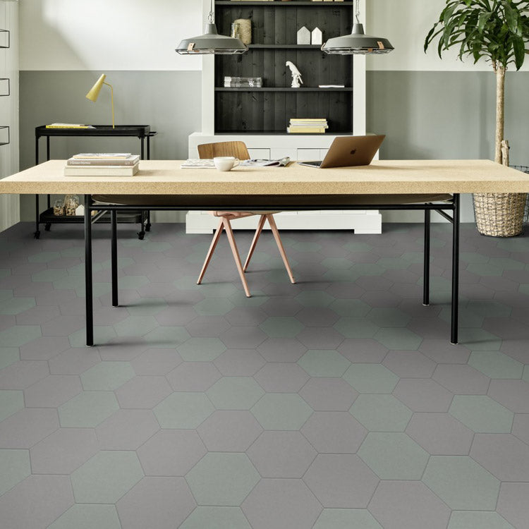 Hexagonvormige tegelvloer in licht en donker grijs met een matte structuur en vlak patroon in een moderne kantoorruimte.