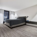 licht grijs eiken vloer met brede planken in een minimalistische slaapkamer met een grijs bed en witte wanden