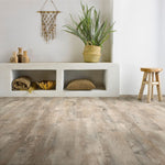 lichte beige eiken vloer met brede planken en subtiele houtnerven in een natuurlijke houtstructuur, sfeerinterieur met lichte wanden, rotan plantenmand, houten kruk en decoratieve accessoires in warme aardetinten