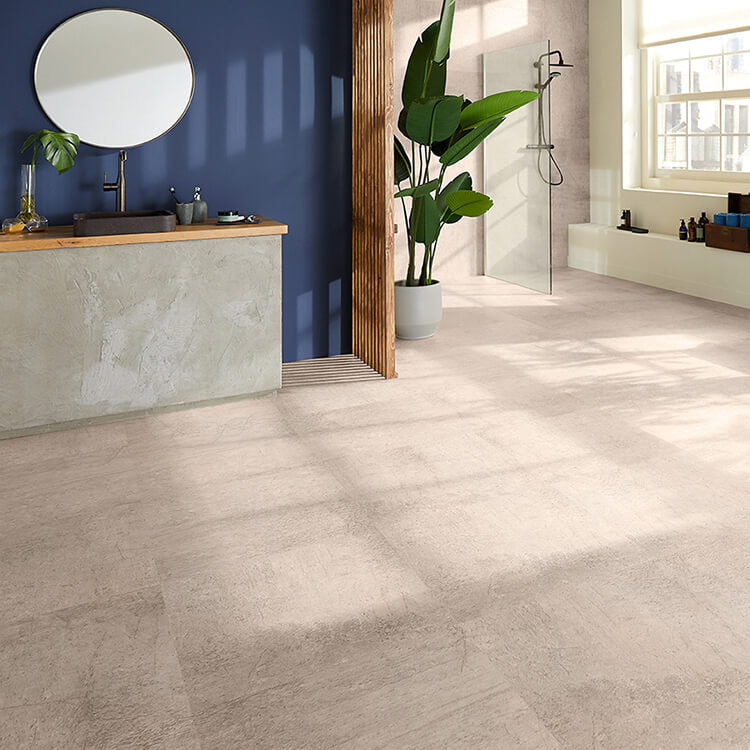 lichte zandkleurige tegelvloer met grote vierkante tegels en subtiele structuur in een lichte grijs-beige tint, moderne badkamer met glazen douchewand en donkere houten accenten tegen een blauwe muur