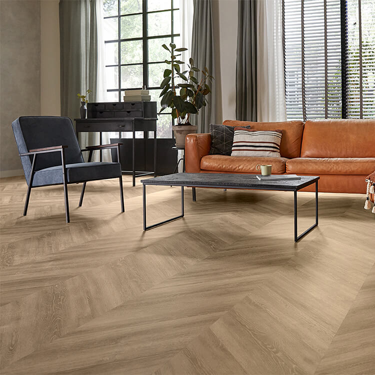 licht eiken visgraatvloer met subtiele houtnerfstructuur in een moderne woonkamer met cognac kleurige leren bank en donkerblauwe fauteuil