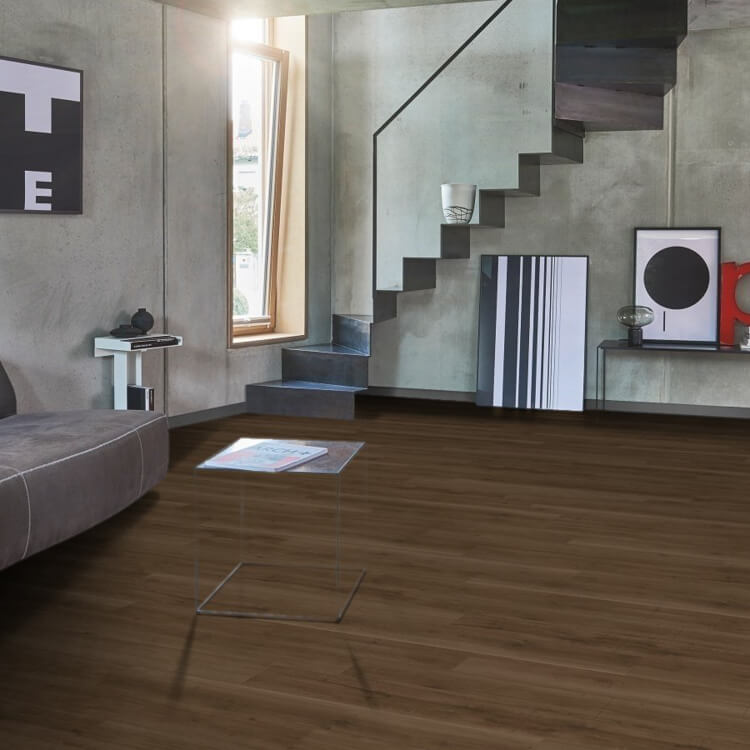 Donker bruin vloer met brede planken en een subtiele houtstructuur in een moderne woonkamer met grijze betonnen muren en zwarte zwevende trap.