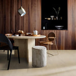 lichte beige vloer met subtiele structuur, eenvoudige effen afwerking in moderne eetkamer met ronde licht natuursteen tafel en donkere houten wandbekleding met verticale lamellen