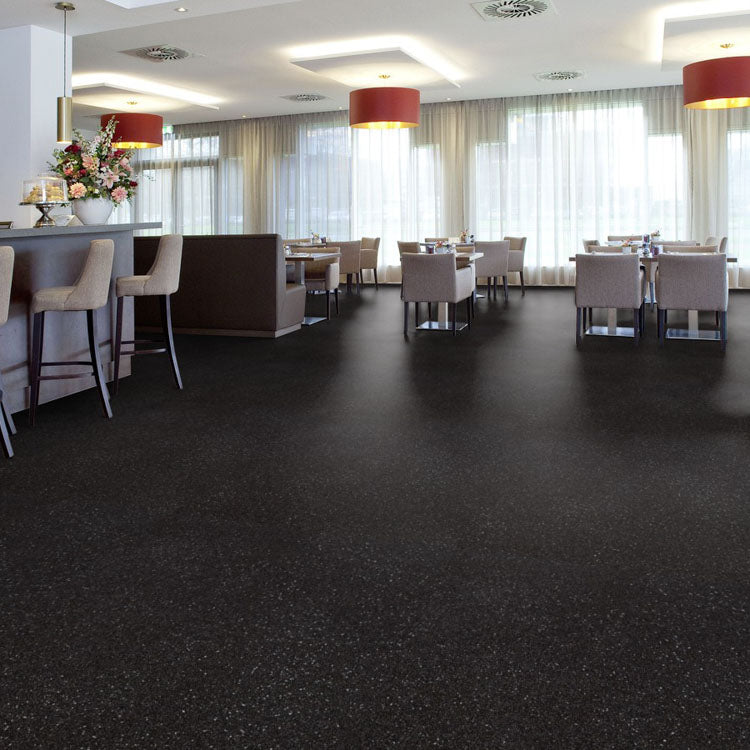 donkergrijze tegelvloer met kleine lichte vlekken in een fijne matte structuur, toegepast in een modern restaurantinterieur met lichtbruine stoelen en rode plafondlampen