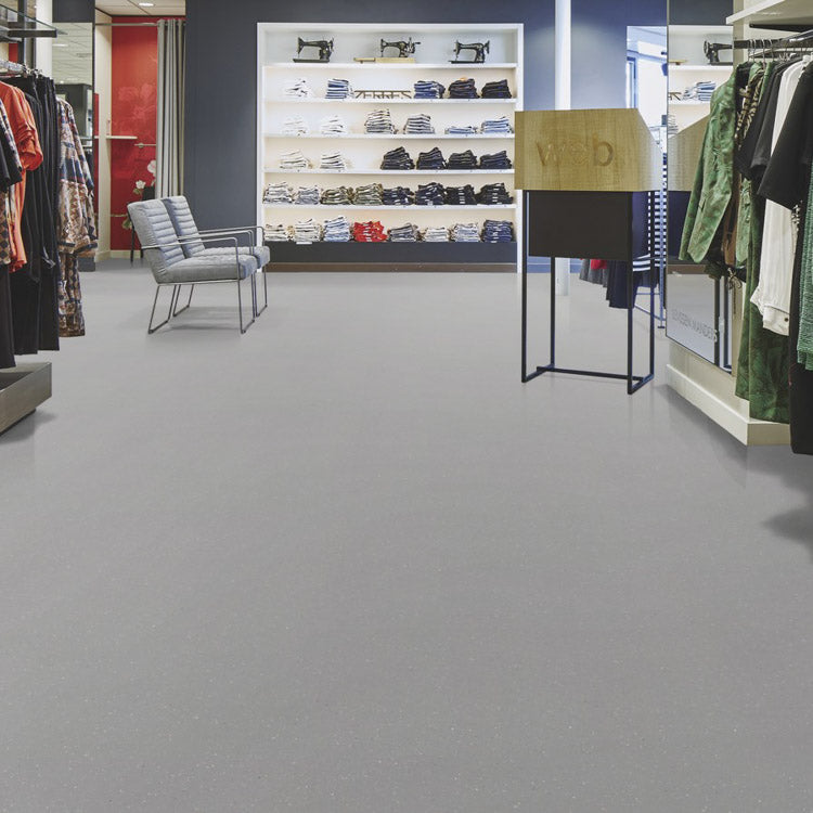 lichte grijs tegelvloer met fijne korrelstructuur in een winkelinterieur met kledingrekken en metalen stoelen