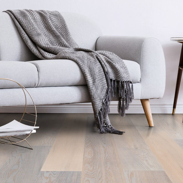 licht beige eiken vloer met brede planken en zichtbare houtnerf in een moderne woonkamer met grijze bank en grijs geruite deken