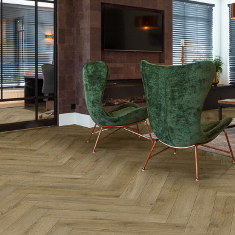 licht eiken vloer met visgraat patroon en brede planken in moderne woonkamer met groene velours fauteuils en donkere wandbekleding