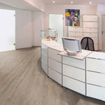 lichte beige eiken vloer met brede planken in een rechte patroon in strak, modern kantoor interieur met witte balie en abstracte kleurrijke schilderij aan de muur