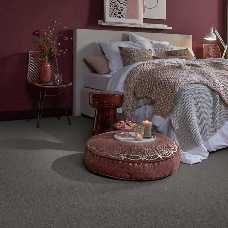 Donkergrijs tapijt met fijne gestructureerde pool in slaapkamer met bordeauxrode wand, lichtgrijze bedbekleding en terracotta accessoires