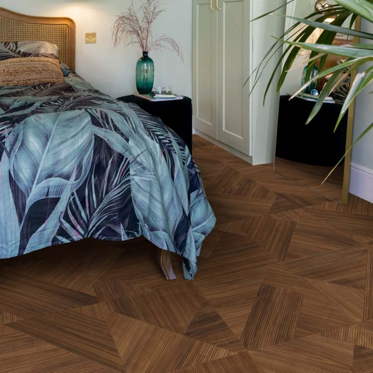 Donker bruin eiken vloer met een geometrisch patroon van vierkante vlakken, elk bestaande uit fijne lineaire nerfstructuren in wisselende richtingen, slaapkamerinterieur met bed en planten.