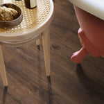 donkerbruin eiken vloer met brede planken en natuurlijke houtstructuur onder een lichte ronde tafel en een roze fluwelen stoelvoet