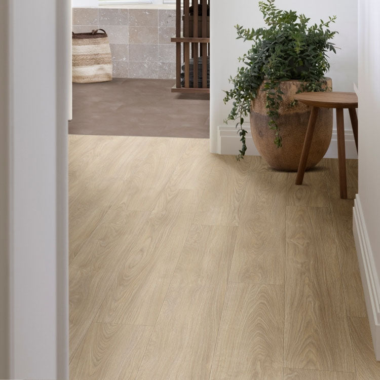 licht beige eiken vloer met brede planken, subtiele houtstructuur en natuurlijke nerven, sfeervolle ruimte met grote pot en houten krukje tegen witte wand
