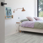 lichte eiken vloer met subtiele houtnerfstructuur in brede planken in een modern slaapkamerinterieur met lichtgroene en lila bedtextiel en een transparant nachtkastje naast het bed