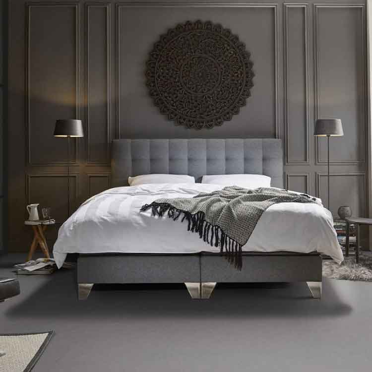 donkergrijze vloer met effen structuur in slaapkamer, combinatie met grijs gestoffeerd bed, wit beddengoed en aangesloten donkergrijze wand met decoratief rond reliëfpaneel