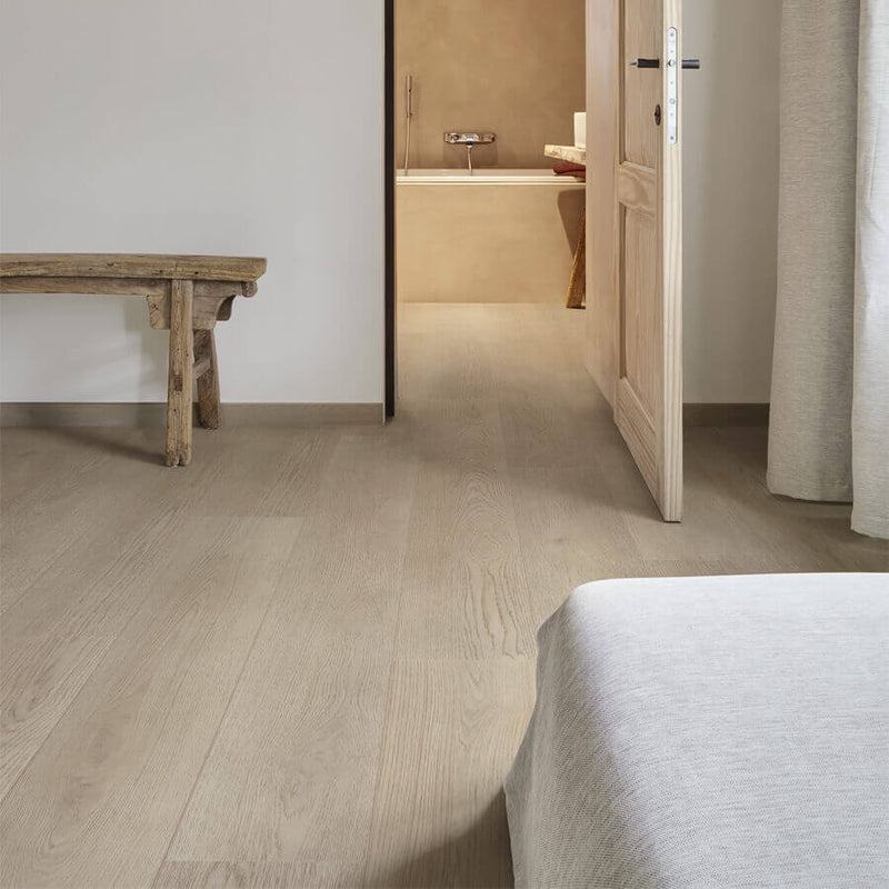 lichte beige eiken vloer met brede planken en subtiele houtnerfstructuur in een minimalistische slaapkamer met een lichte houten deur en een rustieke houten bankje naast een effen lichtgrijze muur