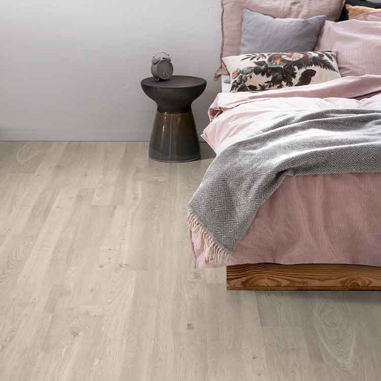 lichte vloer in licht eiken kleur met subtiele houtstructuur en brede planken, gecombineerd met een roze bed en zachte grijs-tinten in het dekbed en kussens