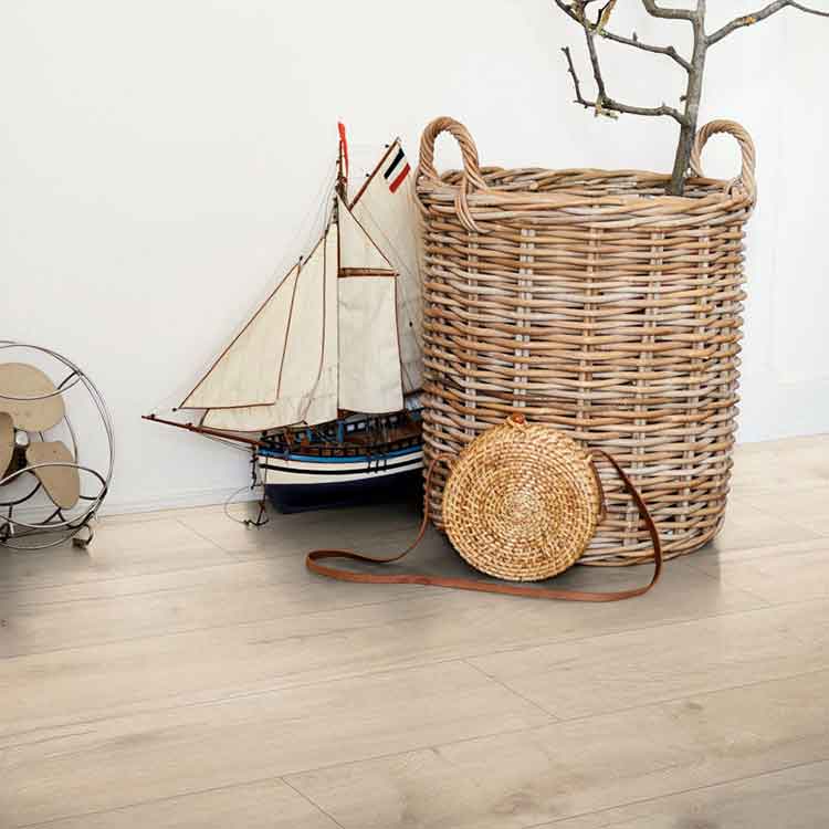 lichte beige eiken vloer met brede planken en subtiele houtnerfstructuur in een Scandinavisch interieur met een rieten mand, rond gevlochten tasje en een model zeilboot