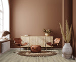lichte eiken vloer met subtiele houtnerfstructuur en brede planken in een lichte, natuurlijke tint onder een woonkamerinterieur met cognacbruine leren stoelen en een beige handgeweven vloerkleed met franjes